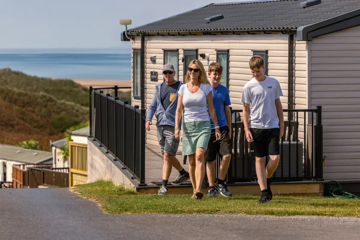Whiteford bay, family walking on the park, with caravan and decking in the background plus beach in the far background